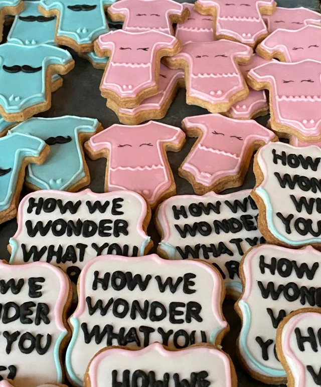 Baby shower onesie cookies with How we wonder what you are plaques