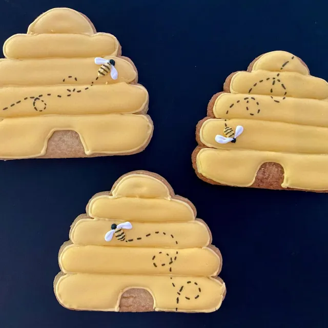 Beehive cookies with tiny piped bees on a navy background