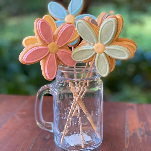 Flower cookies on sticks arranged in a glass jar