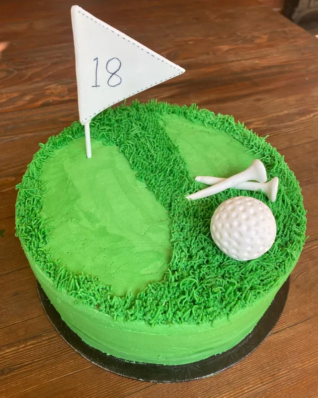 Green golf course cake with a flag and golf ball