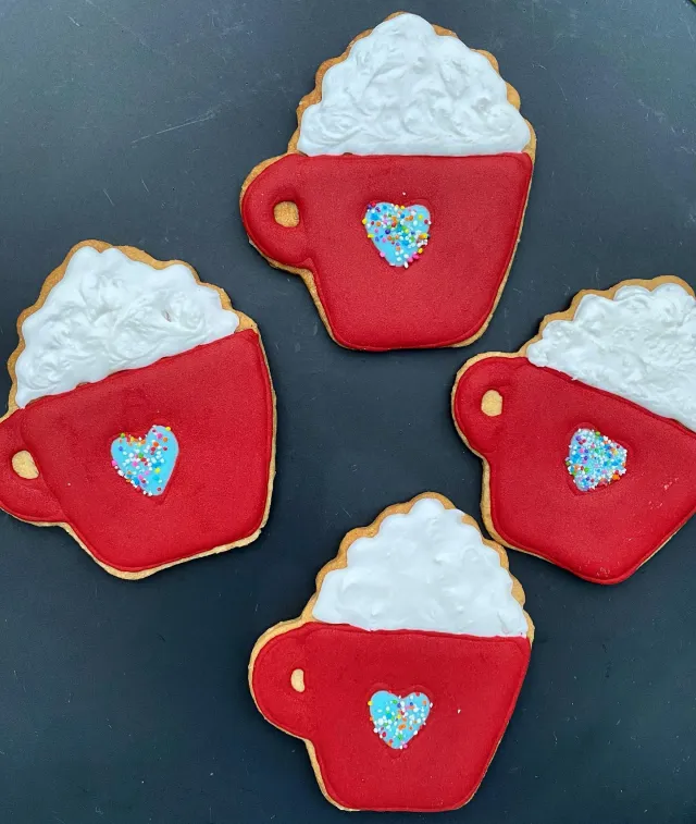 Red mug cookies topped with whipped cream and sprinkle hearts