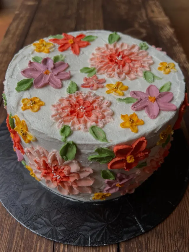 White cake piped with orange, pink and purple buttercream flowers