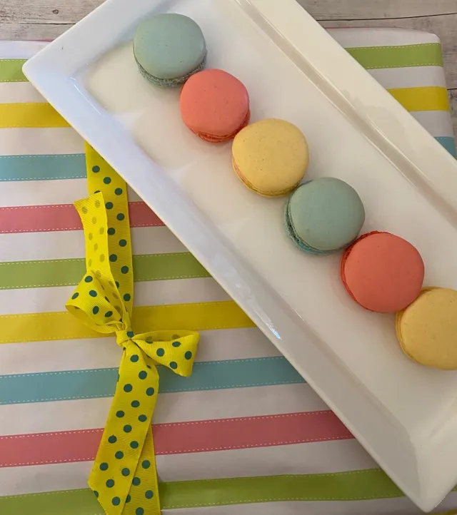 A row of pastel macarons on a white plate