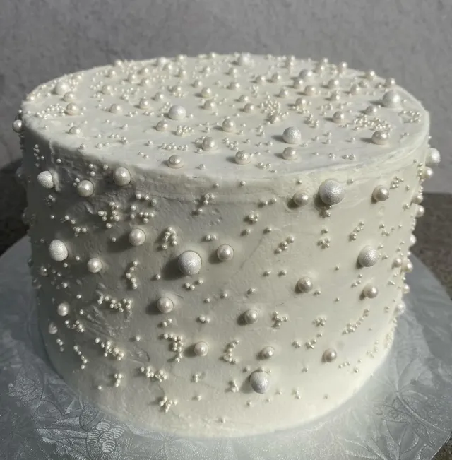 White buttercream cake covered in sugar pearls