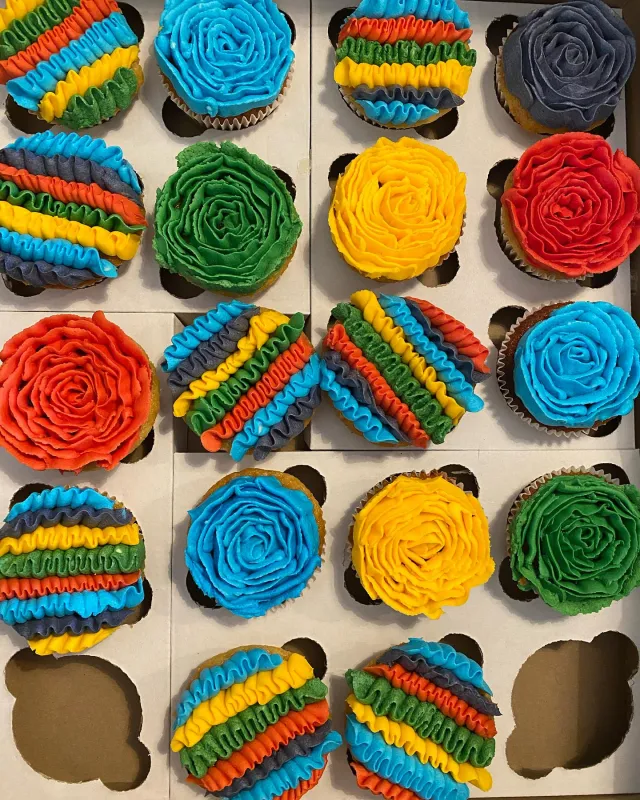 Box of cupcakes piped in rainbow stripes and rosettes