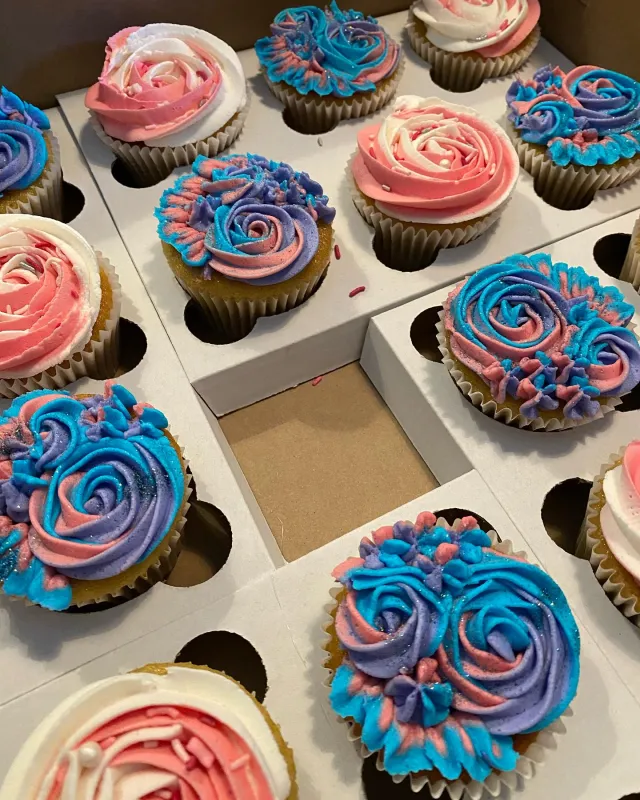Cupcakes piped with pink and blue buttercream roses